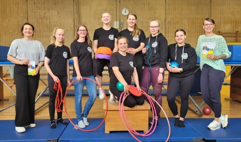 Sportlerinnen und Verwaltungsmitarbeitende sind auf einem Gruppenfoto in einer Turnhalle zu sehen, sie halten Sportger&auml;te das Programm f&uuml;r Sporteln und Familienspa&szlig; 2024 in den H&auml;nden, &copy; Stadt Bad Salzuflen