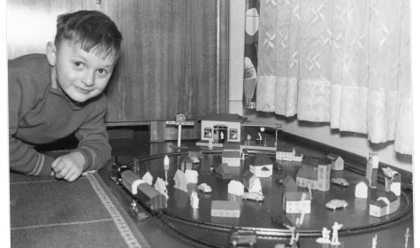 Eine schwarz-weiß Aufnahme von einem Kind, das mit einer Spielzeugeisenbahn spielt, © Dr. Rainer Wittmann