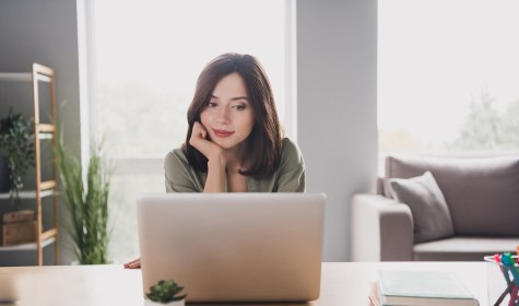Frau sitzt am Schreibtisch und schaut auf einen Laptop, &copy; Adobe Stock