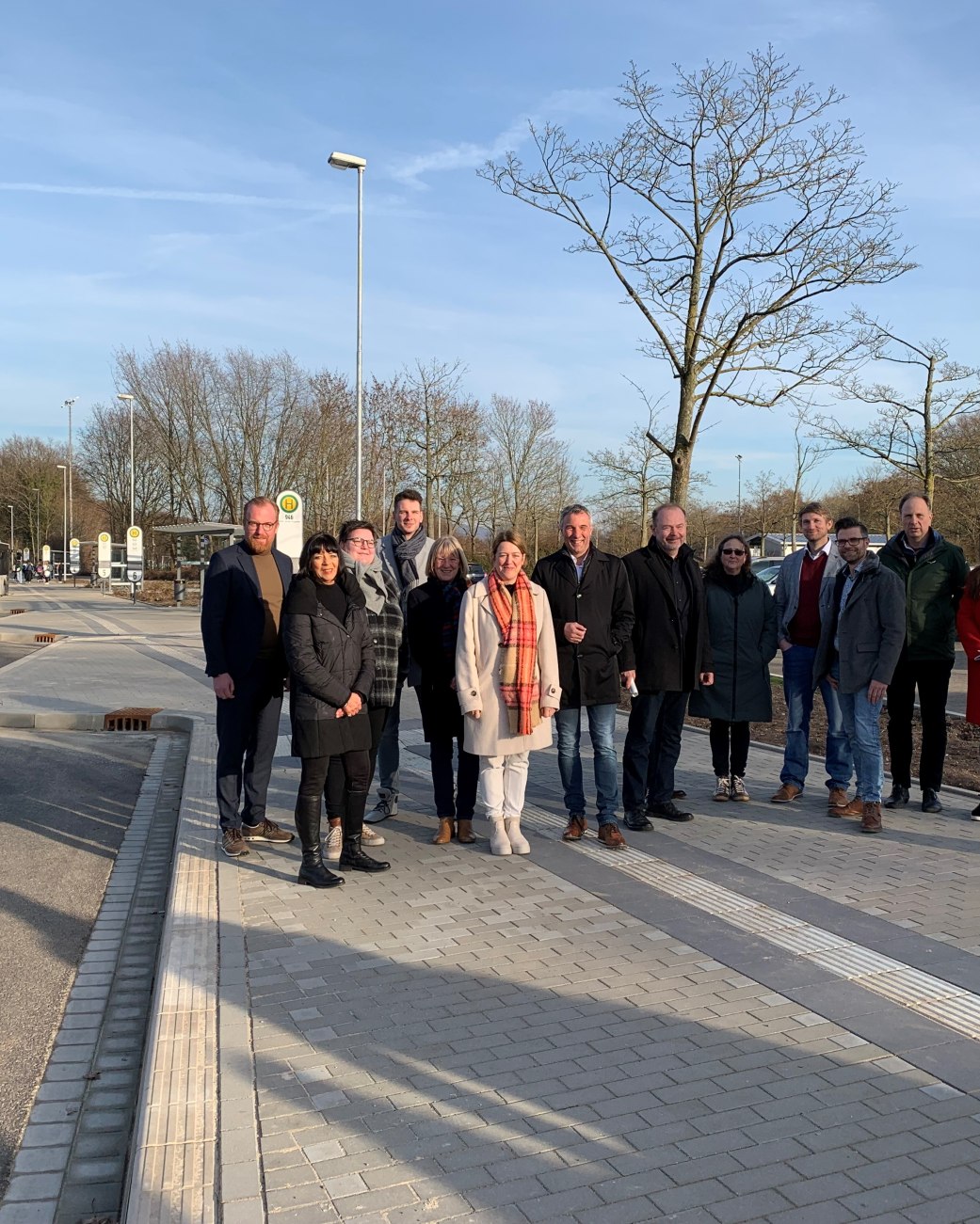 Es sind 14 Personen zu sehen, die auf dem Gelände der neuen Bushaltestelle am Schulnzentrum Aspe stehen, es handelt sich um Vertretende aus den Bereichen Verwaltung, Stadtwerke, Politik, Schule und Baufirma, © Stadt Bad Salzuflen