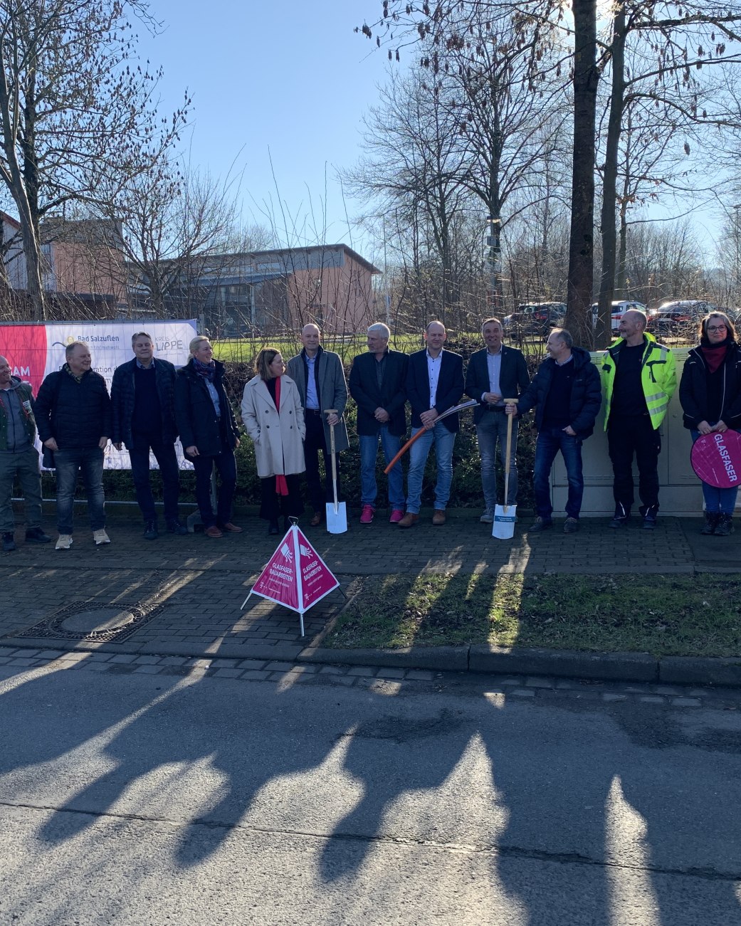 Zu sehen sind 14 Personen, die auf dem Bürgersteig vor der Grundschule Wüsten stehen. Es handelt sich um Vertretende von Stadtverwaltung, Bezirksregierung Detmold, atene KOM (Fördermittelberatungsagentur), Telekom und Berkenkamp + Wüllner (Baufirma), © Stadt Bad Salzuflen