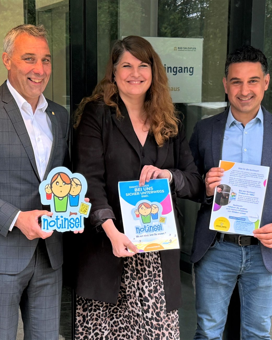 Der erste „Notinsel“-Aufkleber aus der Aktion der Deutschen Kinderschutzstiftung „Hänsel+Gretel und der Stadtverwaltung Bad Salzuflen wird von Bürgermeister Dirk Tolkemitt (links), Anke Hütte (Mitte, Jugendamt, Fachstelle Netzwerk Kinderschutz/Prävention & Koordinierungsstelle Kinderschutz.) und Fatih Gök (Fachdienstleitung Jugendamt) an der Eingangstür des Bad Salzufler Rathauses an der Rudolph-Brandes-Allee angebracht., © Stadt Bad Salzuflen Der erste „Notinsel“-Aufkleber aus der Aktion der Deutschen Kinderschutzstiftung „Hänsel+Gretel und der Stadtverwaltung Bad Salzuflen wird von Bürgermeister Dirk Tolkemitt (links), Anke Hütte (Mitte, Jugendamt, Fachstelle Netzwerk Kinderschutz/Prävention & Koordinierungsstelle Kinderschutz.) und Fatih Gök (Fachdienstleitung Jugendamt) an der Eingangstür des Bad Salzufler Rathauses an der Rudolph-Brandes-Allee angebracht., © Stadt Bad Salzuflen