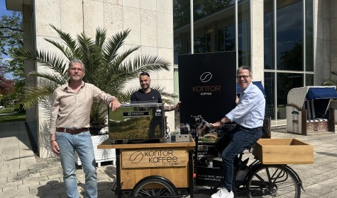 Genuss unter freiem Himmel: Das Coffee-Bike von Kontor Kaffee ist ab dem 1. Mai regelmäßig auf der Wandelbar-Terrasse im Kurpark Bad Salzuflen im Einsatz. Präsentieren das neue Angebot (v. l.): Ralf Hammacher (Fachbereichsleiter Touristik, Gesundheit und Kultur), Barista Jerwin Derbas und Hendrik Krömker (Geschäftsführer von Kontor Kaffee). , © Stadt Bad Salzuflen