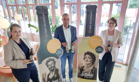 Natursolehaltige Durstlöscher für die Kurstadt: Bad Salzuflens Bürgermeister Dirk Tolkemitt (Mitte), Kurparkhotel-Inhaberin Swetlana Lenger (links) und Myriam Heidemann (rechts, Fachdienstleiterin Kulturelle Bildung, Event und Stadtmarketing)
freuen sich, die neuen Getränkesorten „Gustavs Helles Sole-Bier“ und „Sophies Sole-Limo“ am 23. Juli auf
dem Roten Platz vor dem Kurgastzentrum offiziell vorzustellen., © Stadt Bad Salzuflen