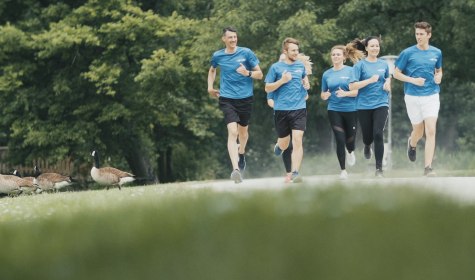 Mehrere Läufer sind zu sehen, sie tragen das gleiche blaue Outfit