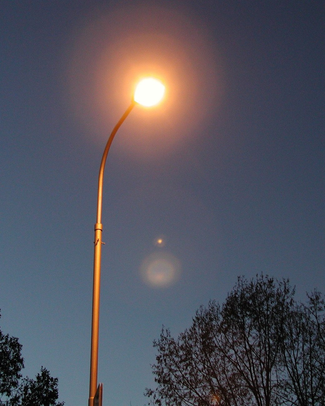 Zu sehen ist eine angeschaltete Straßenlaterne, es ist Nacht