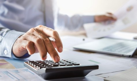 Eine Hand tippt auf einem Taschenrechner auf einem Schreibtisch, © stock.adobe.com | lovelyday12 Eine Hand tippt auf einem Taschenrechner auf einem Schreibtisch, © stock.adobe.com | lovelyday12
