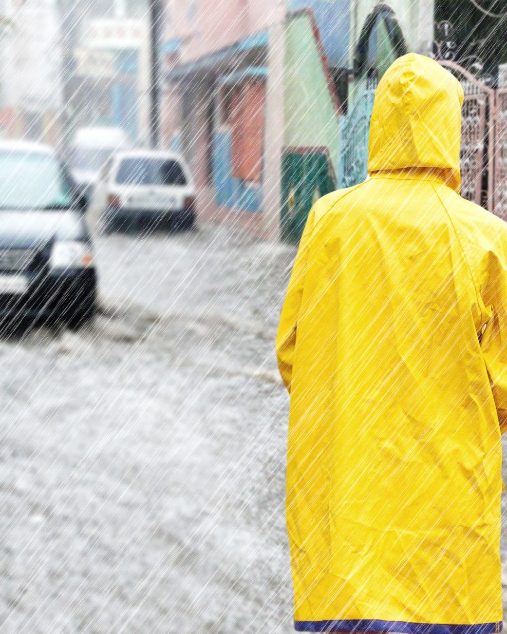 Starker Regen hat eine Straße überflutet, im Vordergrund ist eine Person mit gelben Regenmantel zu sehen., © Jürgen Fälchle - stock.adobe.com