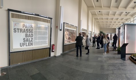 Zu sehen ist eine Panoramaaufnahme in der Wandelhalle, mehrere Personen stehen vor den Schaufenstern, in denen die Modelle der Ausstellung gezeigt werden, © Stadt Bad Salzuflen