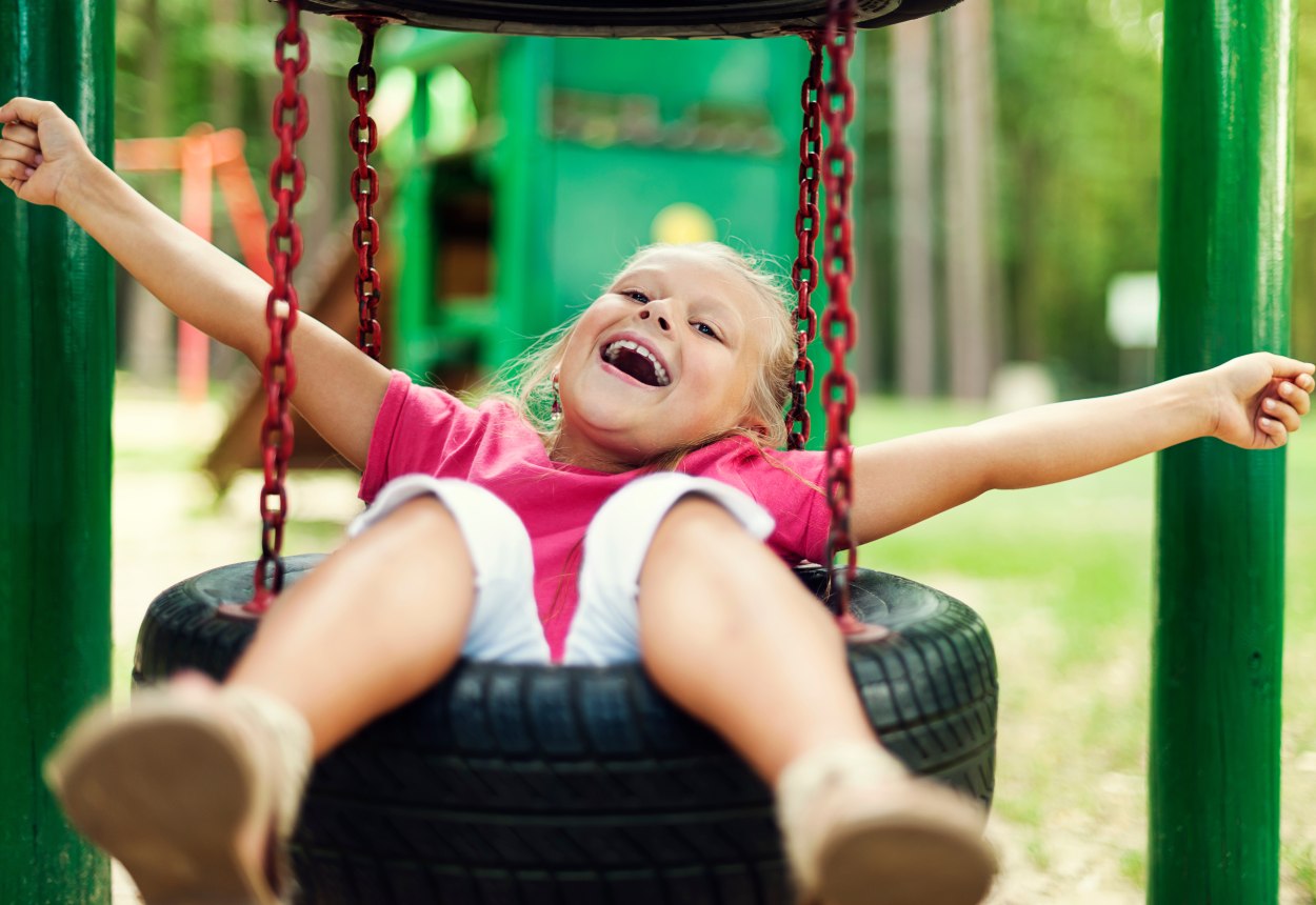 Ein Kind schaukelt mit in die Luft gestreckten Armen auf einer Reifenschaukel., © gpointstudio - stock.adobe.com