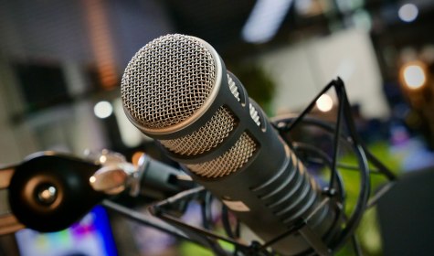Nahaufnahme eines professionellen Mikrofonkopfs mit Metallgitter und Halterung vor unscharfem Hintergrund, &copy; Pexels / Reel Focus Productions