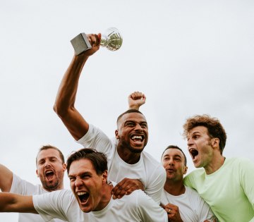 Ein Sportteam feiert den gewonnenen Pokal., © stock.adobe.com - Rawpixel.com