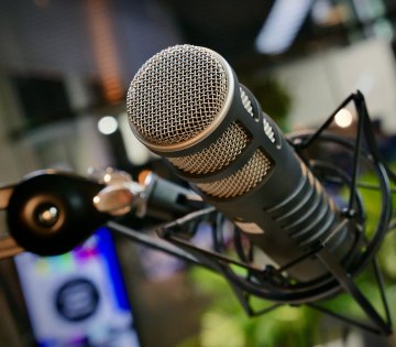 Nahaufnahme eines professionellen Mikrofonkopfs mit Metallgitter und Halterung vor unscharfem Hintergrund, &copy; Pexels / Reel Focus Productions