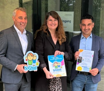 Der erste &bdquo;Notinsel&ldquo;-Aufkleber aus der Aktion der Deutschen Kinderschutzstiftung &bdquo;H&auml;nsel+Gretel und der Stadtverwaltung Bad Salzuflen wird von B&uuml;rgermeister Dirk Tolkemitt (links), Anke H&uuml;tte (Mitte, Jugendamt, Fachstelle Netzwerk Kinderschutz/Pr&auml;vention & Koordinierungsstelle Kinderschutz.) und Fatih G&ouml;k (Fachdienstleitung Jugendamt) an der Eingangst&uuml;r des Bad Salzufler Rathauses an der Rudolph-Brandes-Allee angebracht., &copy; Stadt Bad Salzuflen