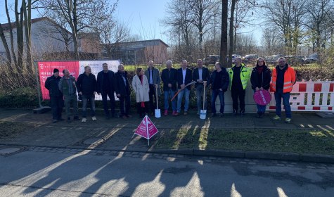 Zu sehen sind 14 Personen, die auf dem Bürgersteig vor der Grundschule Wüsten stehen. Es handelt sich um Vertretende von Stadtverwaltung, Bezirksregierung Detmold, atene KOM (Fördermittelberatungsagentur), Telekom und Berkenkamp + Wüllner (Baufirma), © Stadt Bad Salzuflen